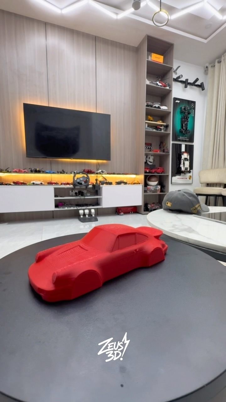 A red 3D-printed sports car model on a desk.