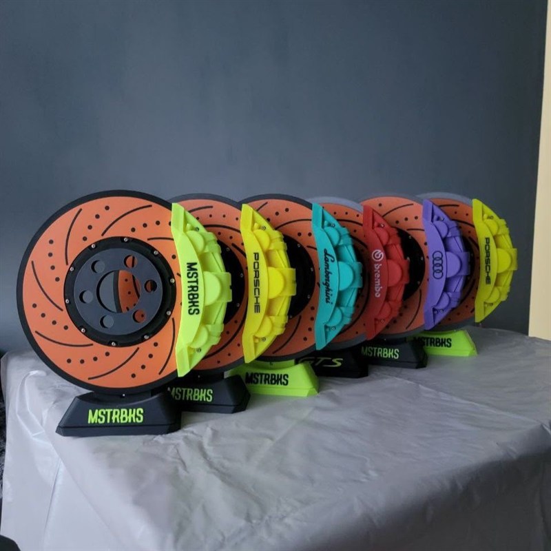 A row of 3D-printed brake disc coasters in several colours.